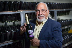 Robert Mazza holding SCCA special label sparkling wine, Mazza Wines national sponsor and "Official Sparkling Wine" for SCCA [Photo courtesy of Robert Mazza, Inc.]